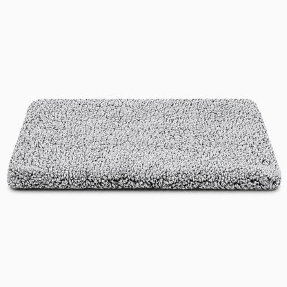 Tapis chauffant chien avec surface souple grise dans un panier, créant un espace douillet pour le repos